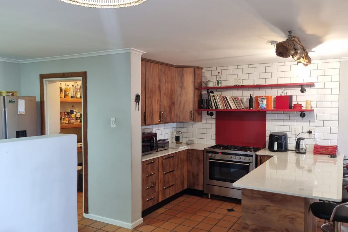 A functional kitchen featuring wood-look cabinetry, white subway tile backsplash, stone countertops, a gas stove, and an adjacent walk-in pantry.