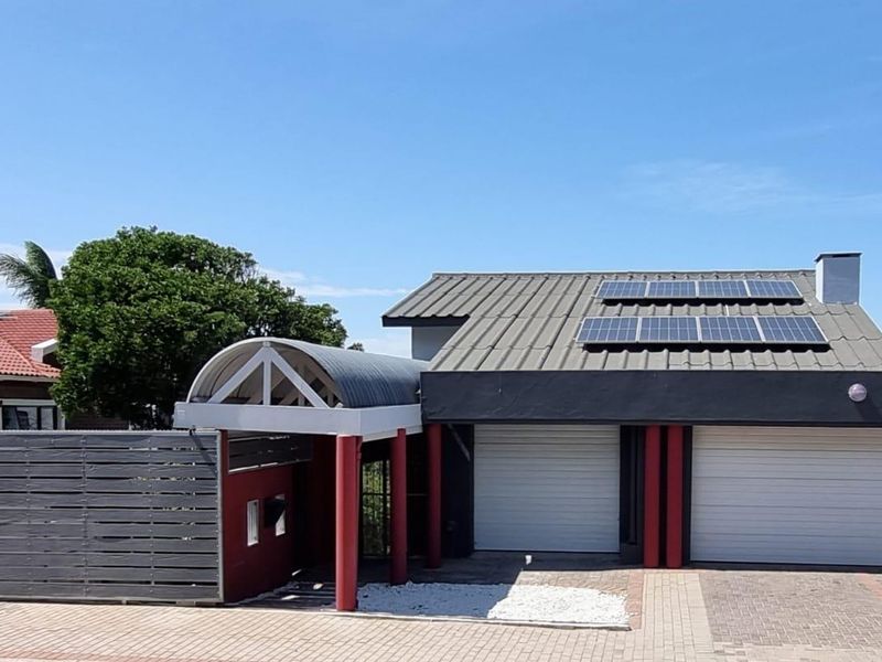 Front exterior view of the property featuring a double garage, solar panel installation on the roof, and a covered entrance walkway.