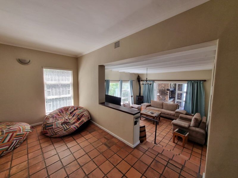 Spacious split-level living area featuring terracotta tiled flooring, a built-in fireplace, and an open-plan layout connecting the upper and lower lounge spaces.