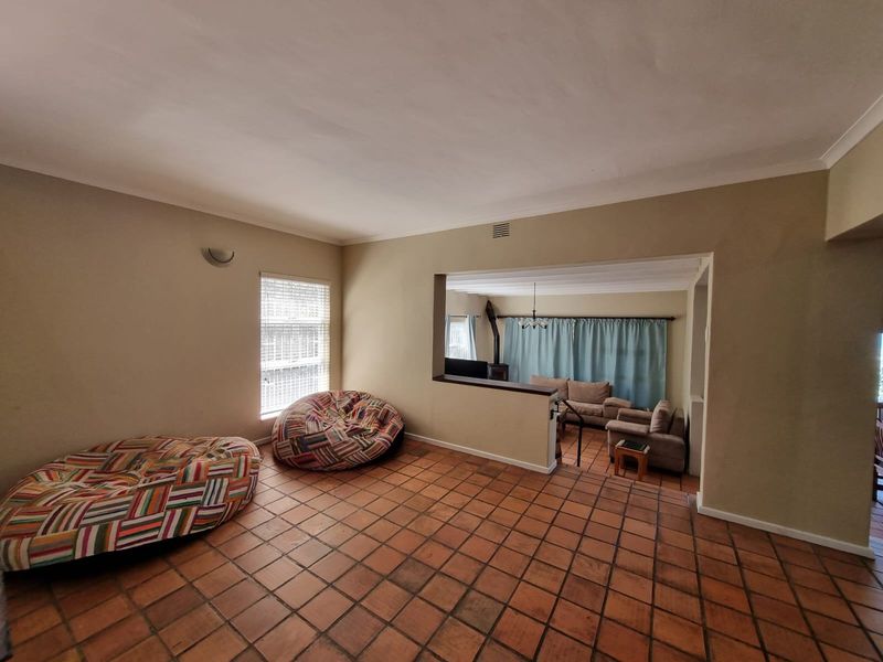 Spacious open-plan living area featuring terracotta floor tiles, a partial room divider, and a secondary sunken lounge area with a fireplace.