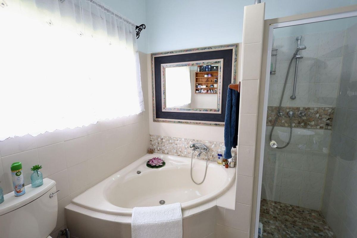 A functional bathroom featuring a corner bathtub, a separate shower enclosure with tiled walls, and a vanity mirror.
