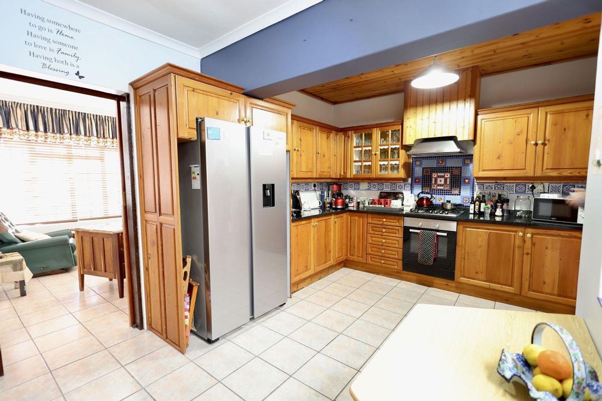 A traditional kitchen featuring solid wood cabinetry, granite countertops, a built-in oven with extractor fan, and tiled flooring.