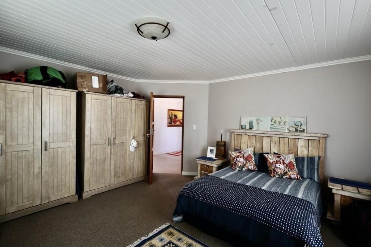 Spacious bedroom featuring a white tongue-and-groove ceiling, neutral wall tones, and carpeted flooring.