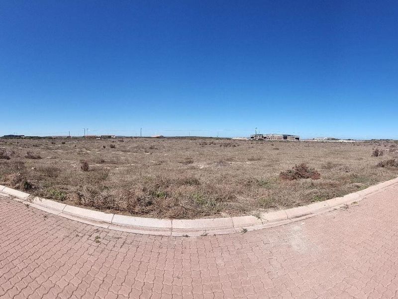 A panoramic view of a vacant commercial development plot featuring paved access roads and installed street lighting.