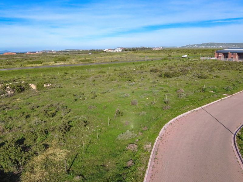 Aerial view of a vacant industrial plot featuring paved road access and perimeter fencing in a developing industrial area.