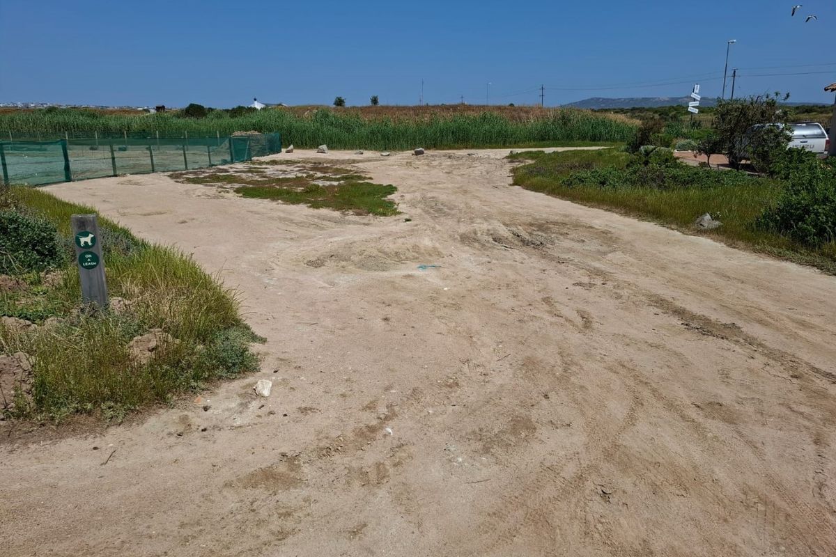 A view of the vacant residential land featuring natural sandy terrain, native vegetation, and perimeter fencing.