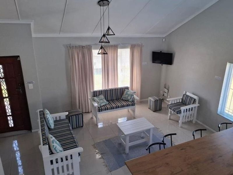 Spacious open-plan living area featuring vaulted ceilings, tiled flooring, and a timber breakfast bar, creating a bright and functional living space.