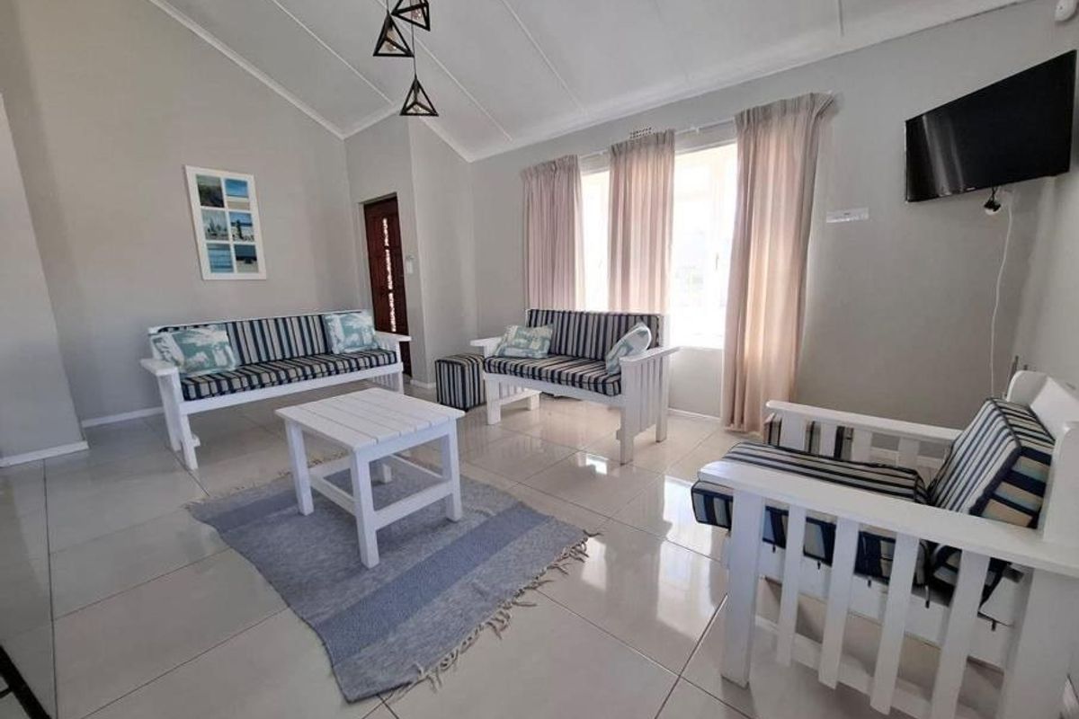 A bright living room featuring vaulted ceilings, large format floor tiles, and neutral wall finishes, providing a clean and open living space.
