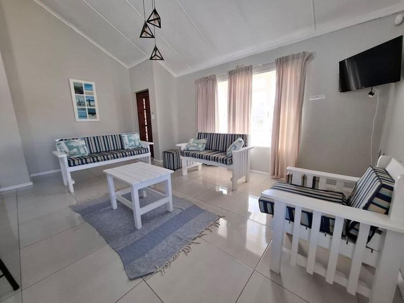 A bright living room featuring vaulted ceilings, large format floor tiles, and neutral wall finishes, providing a clean and open living space.
