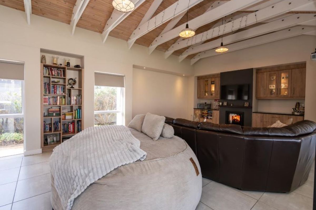 Spacious living room featuring a vaulted timber-clad ceiling with exposed beams, built-in cabinetry, and a cozy fireplace.