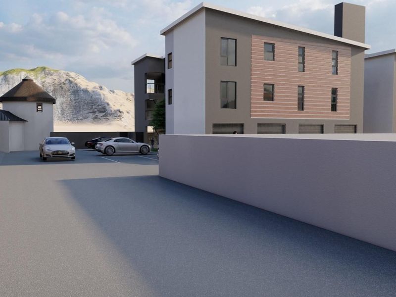 A modern multi-story apartment complex exterior featuring a paved parking area, concrete boundary walls, and integrated garage access.