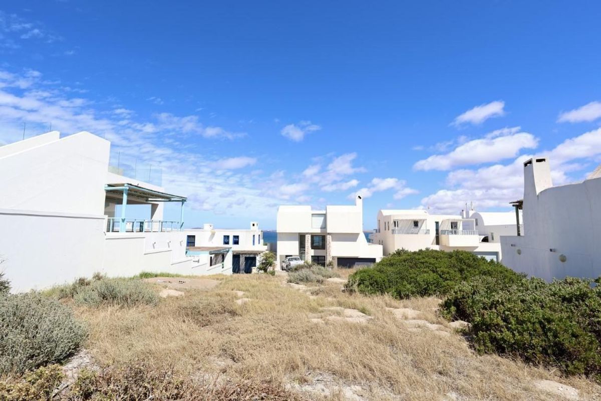 A view of the residential property exterior showing surrounding homes and natural landscape, highlighting the vacant land setting.