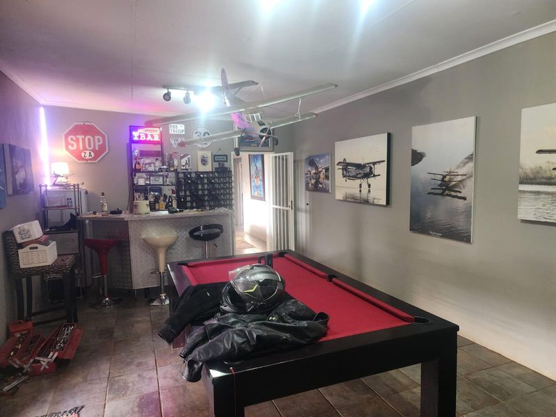 A dedicated bar area featuring a built-in counter, tiled flooring, and cove cornicing, currently utilized as a recreational space.