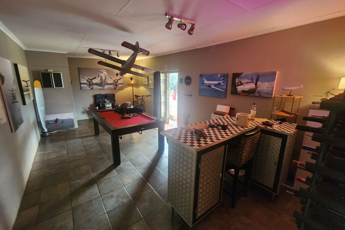 A spacious living area featuring tiled flooring and track lighting, currently utilized as a recreational space with direct access to the outdoors.
