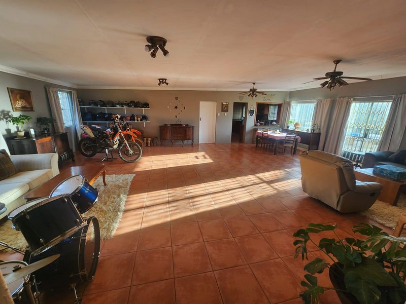 Spacious open-plan living and dining area featuring large format floor tiles, ceiling fans, and abundant natural light through multiple windows.