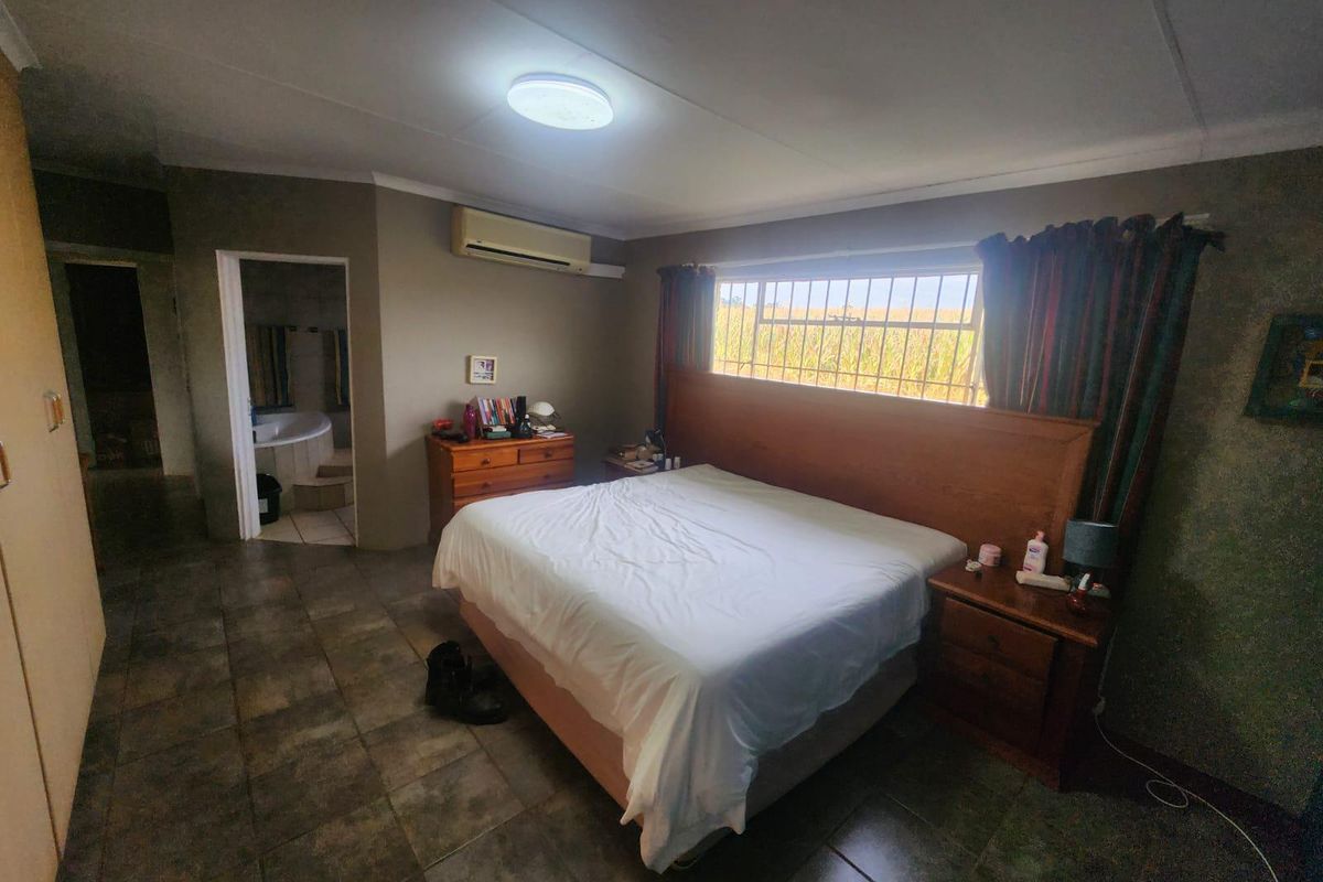 Spacious bedroom featuring tiled flooring, a split-system air conditioner, and direct access to an en-suite bathroom.
