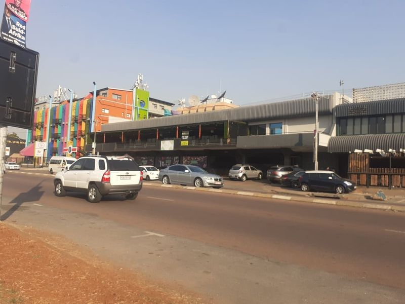Street-level view of a commercial building featuring a multi-level facade with covered balcony areas and ground-floor retail or office frontage.