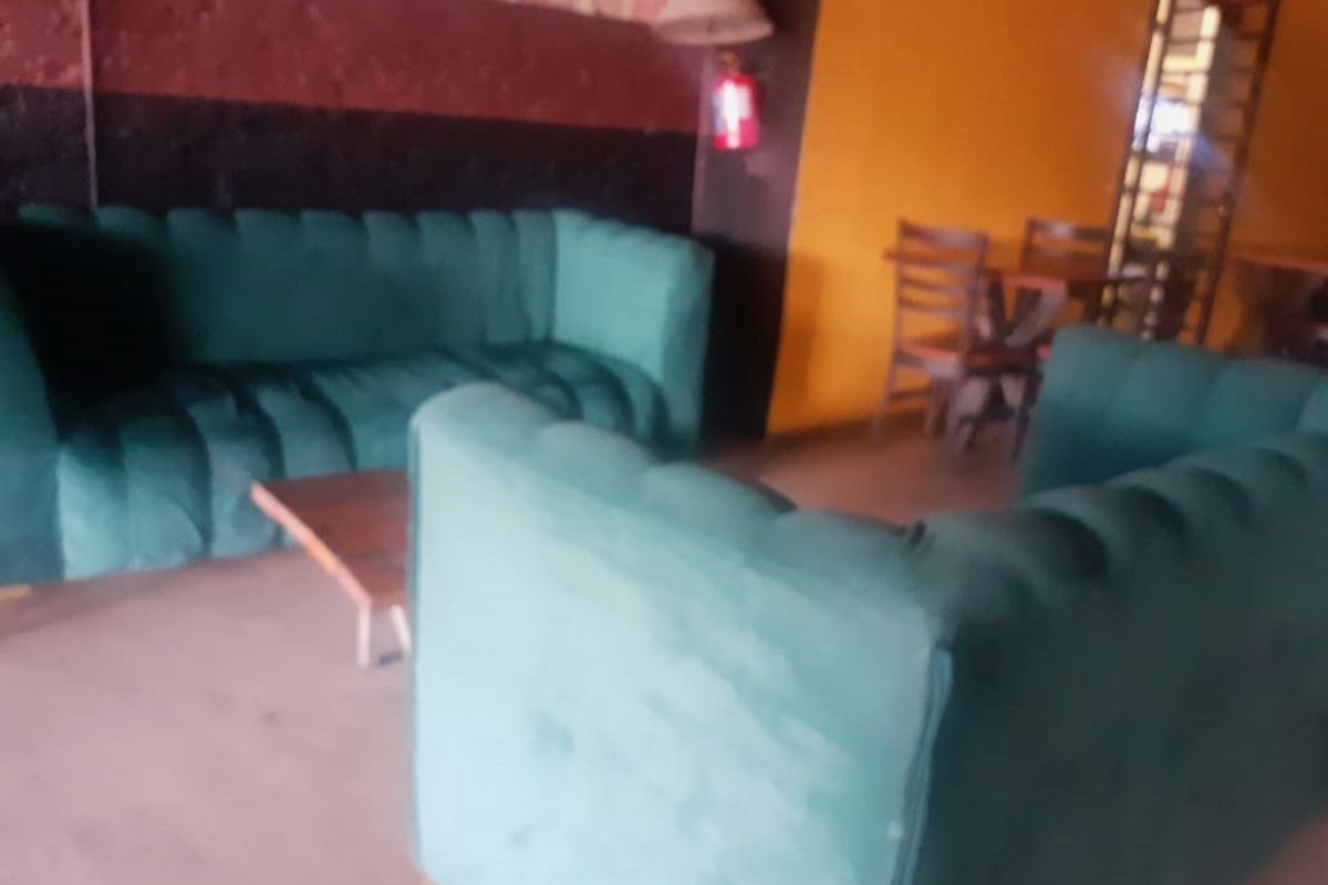 A commercial lounge area featuring bold yellow and dark accent walls, providing a casual seating space for guests or clients.