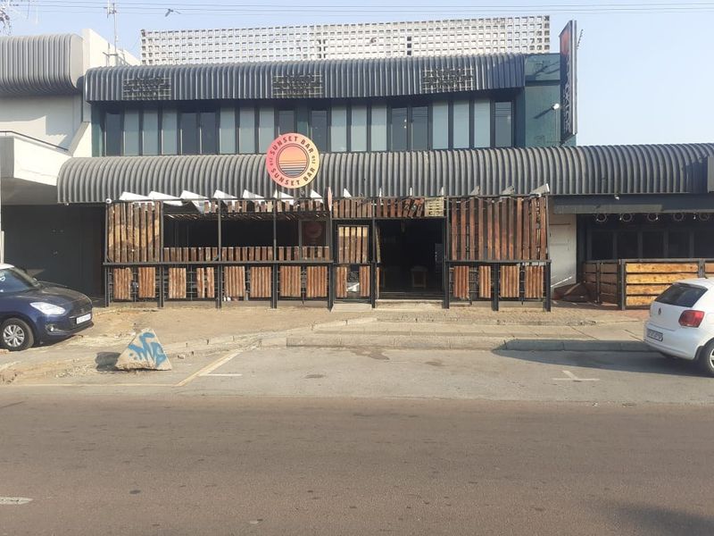 Commercial street-level facade featuring a bar entrance with timber slat cladding and metal awning structure.