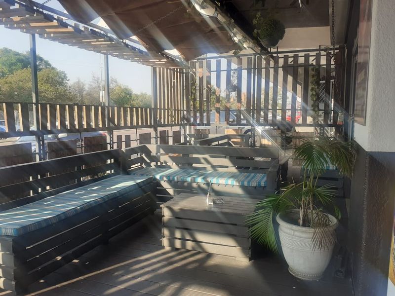 A covered outdoor patio area featuring timber decking, slatted privacy screens, and a retractable awning, suitable for commercial outdoor seating.