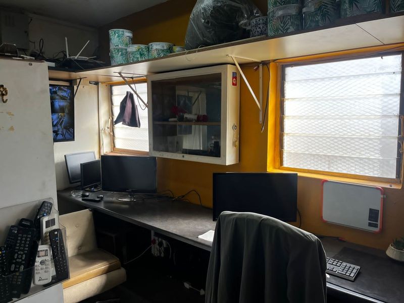 A functional office space featuring a built-in desk, wall-mounted storage cabinetry, and dual windows providing natural light.