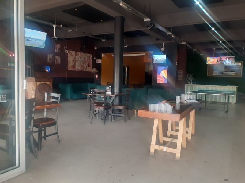 Spacious open-plan commercial interior featuring exposed ceiling infrastructure, central support column, and versatile layout suitable for a bar or entertainment venue.