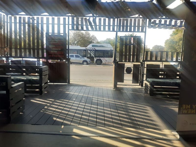 A covered outdoor patio area featuring timber decking and slatted privacy screening, providing a semi-enclosed space with direct street access.