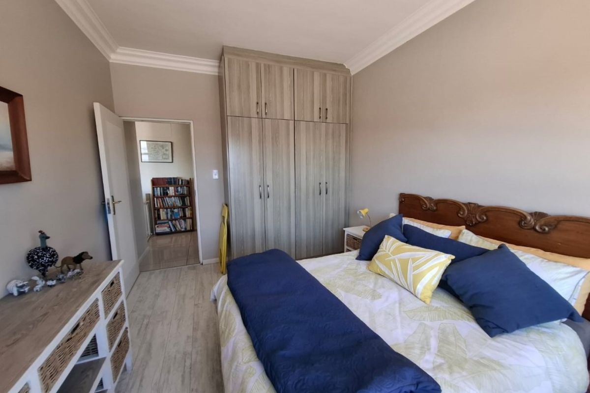 A well-maintained bedroom featuring built-in wooden cabinetry, crown molding, and light-toned flooring, offering a clean and functional living space.