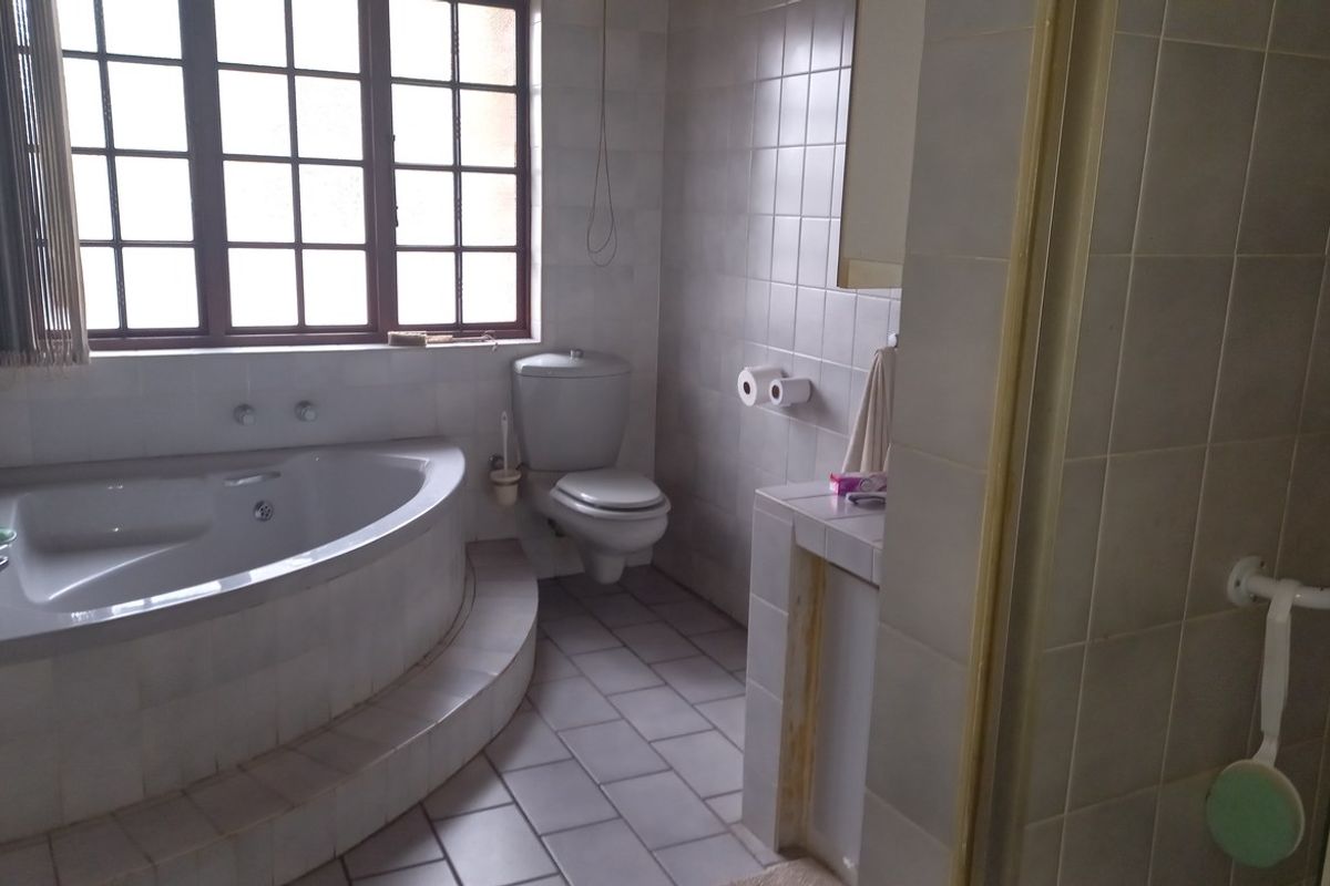 A functional bathroom featuring a corner bathtub, tiled flooring, and wall-mounted toilet, offering a classic layout with potential for modernization.