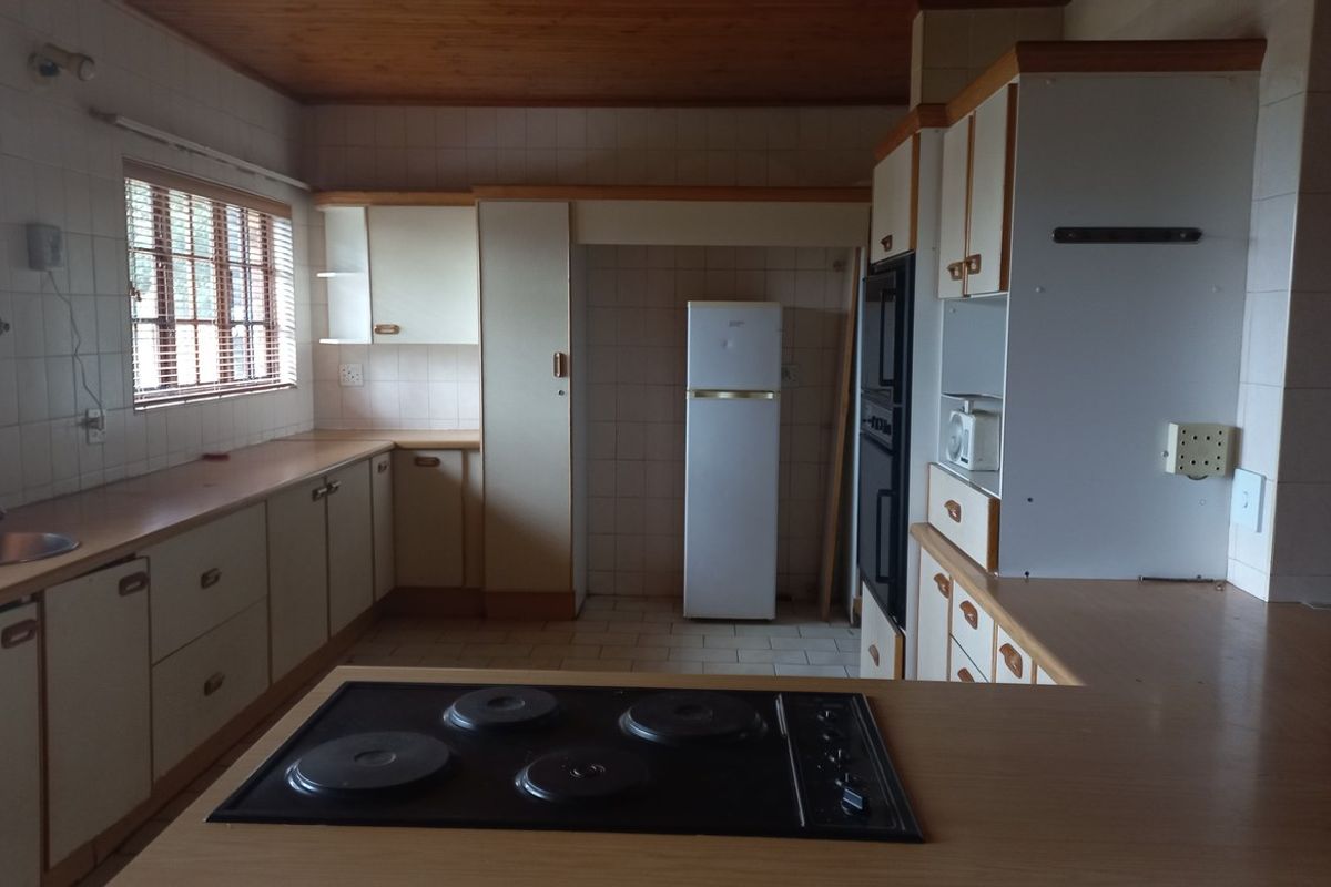 A spacious kitchen featuring built-in cabinetry, a fitted electric hob, double wall oven, and tiled wall finishes.