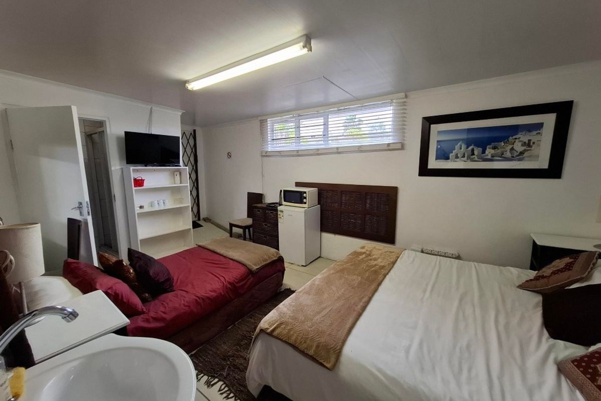 A bedroom featuring an integrated vanity sink, tiled flooring, and a functional layout with built-in window blinds.