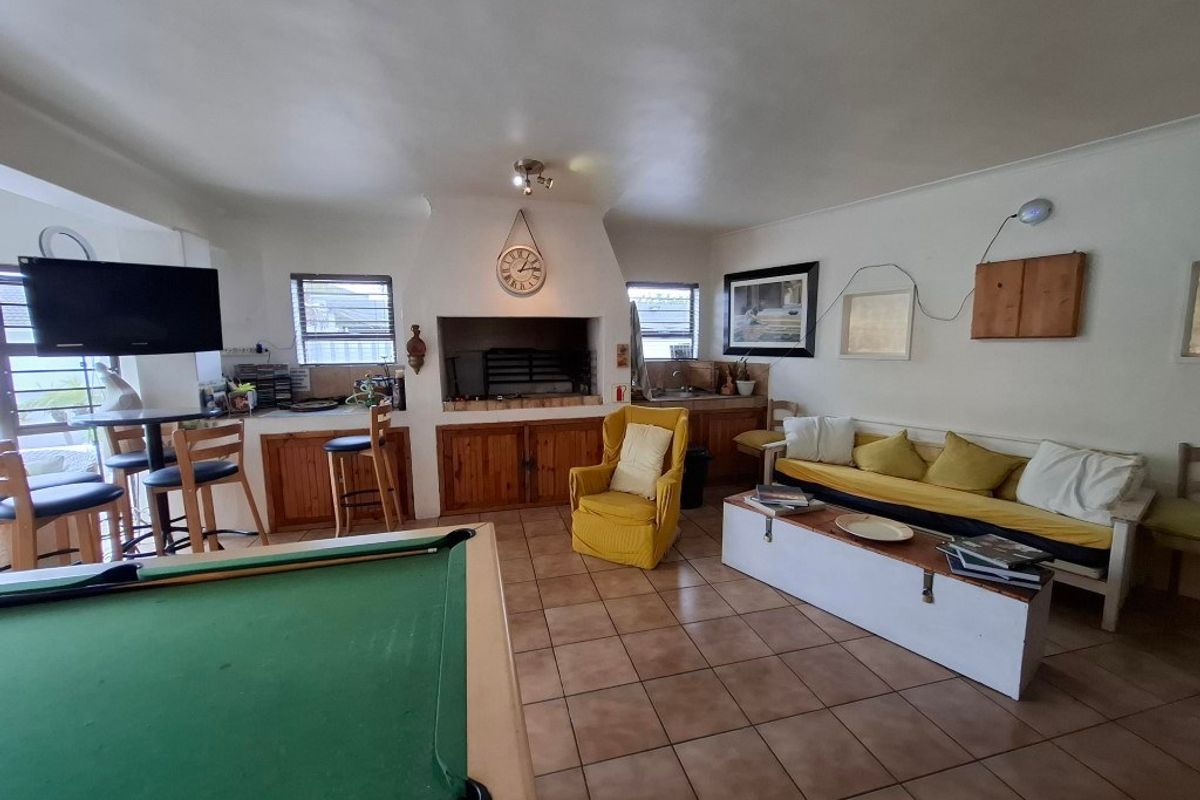 Spacious entertainment room featuring a built-in indoor braai, tiled flooring, and integrated cabinetry, ideal for social gatherings and leisure activities.
