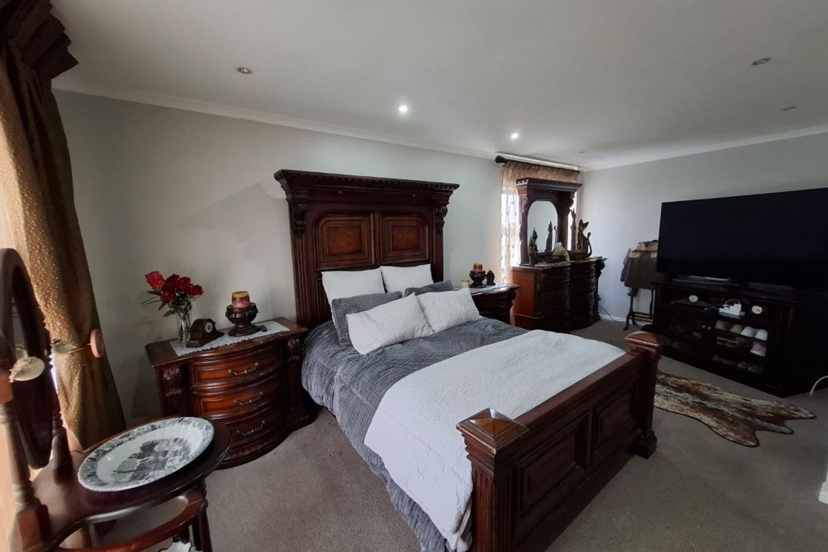 Spacious bedroom featuring neutral wall tones, recessed ceiling lighting, and carpeted flooring.