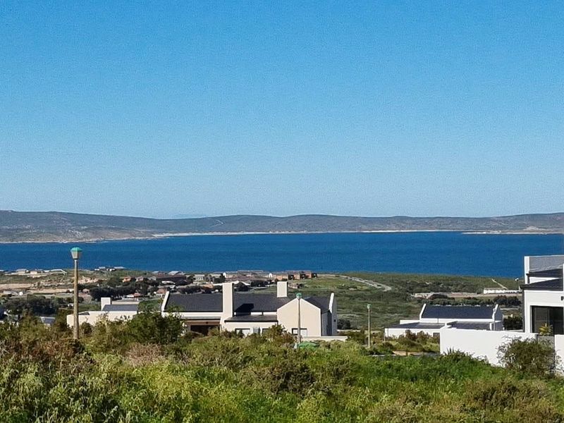 A scenic elevated view overlooking the coastal landscape, surrounding residential properties, and the distant bay.