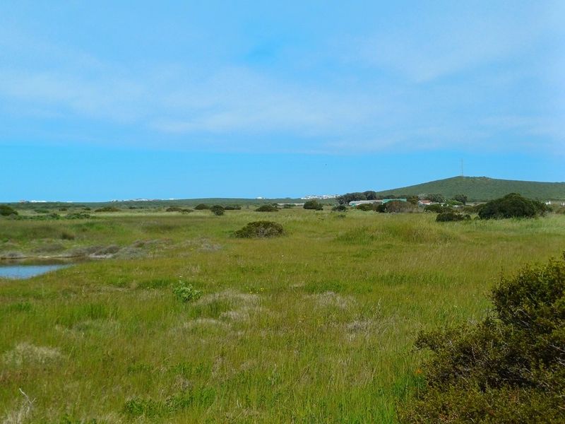 A wide-angle view of the vacant residential land, featuring natural coastal vegetation, open grassy terrain, and distant landscape views.