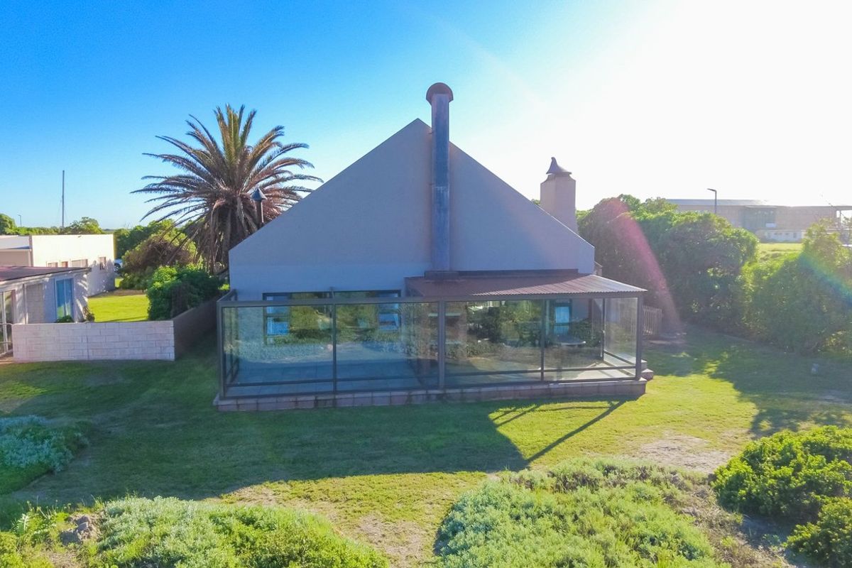 Rear view of the property featuring an enclosed patio area, a prominent chimney, and a spacious garden setting.
