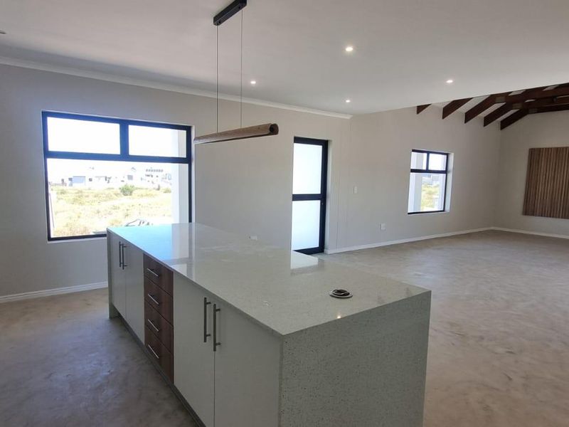 Spacious open-plan living area featuring a modern kitchen with a central island, quartz countertops, gas stove, and exposed timber ceiling beams.