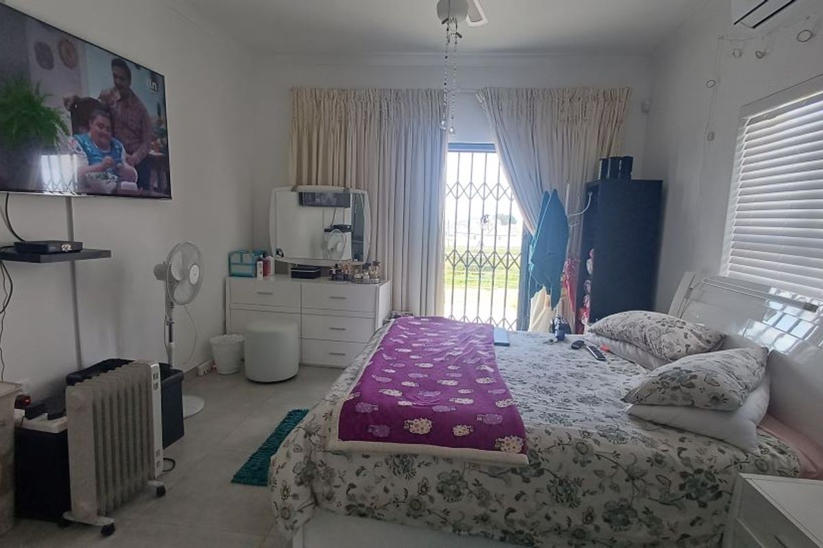 A bedroom featuring tiled flooring, a ceiling fan, and a security gate leading to an outdoor area.