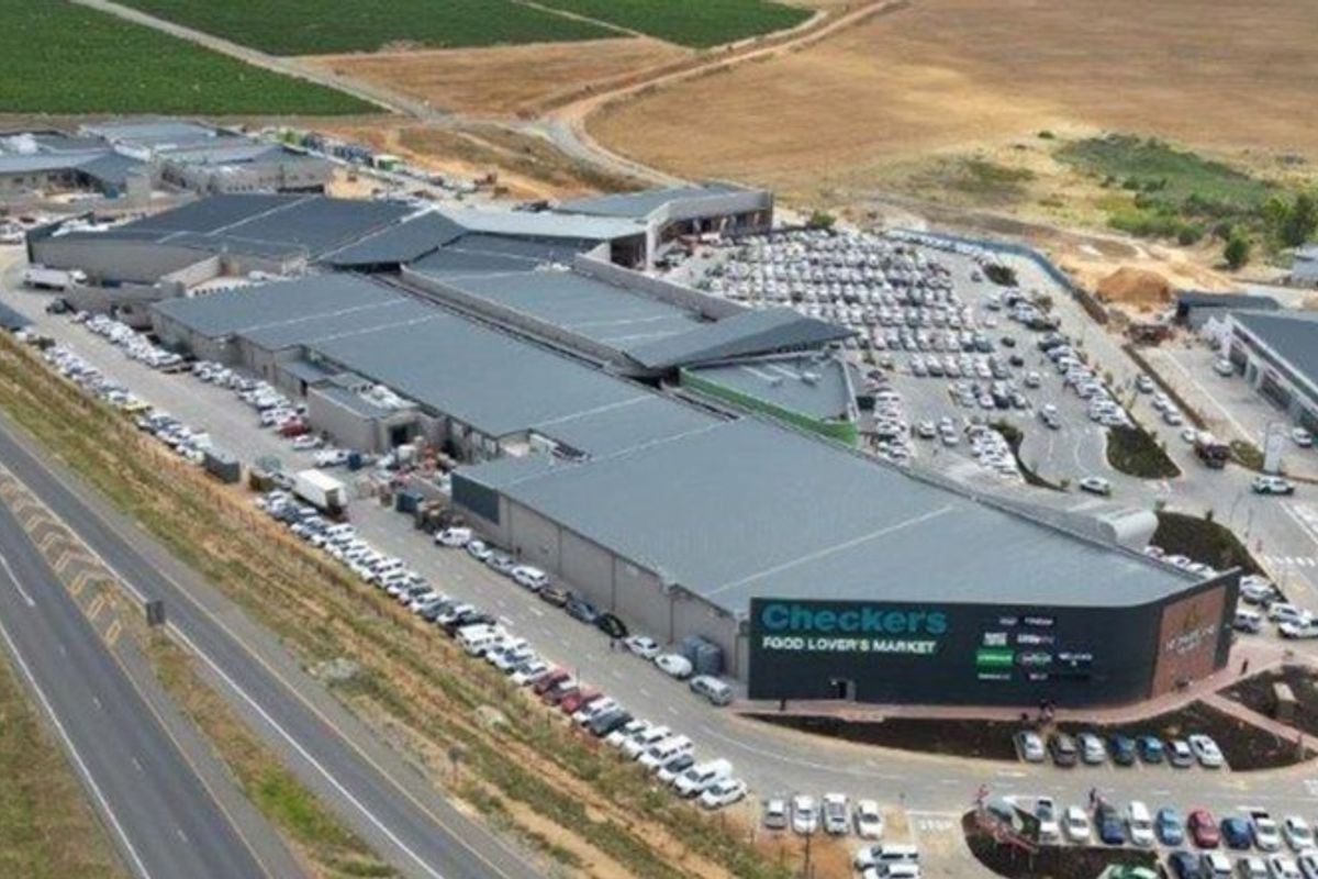 Aerial view of a large commercial shopping center complex featuring extensive parking facilities and direct highway access.