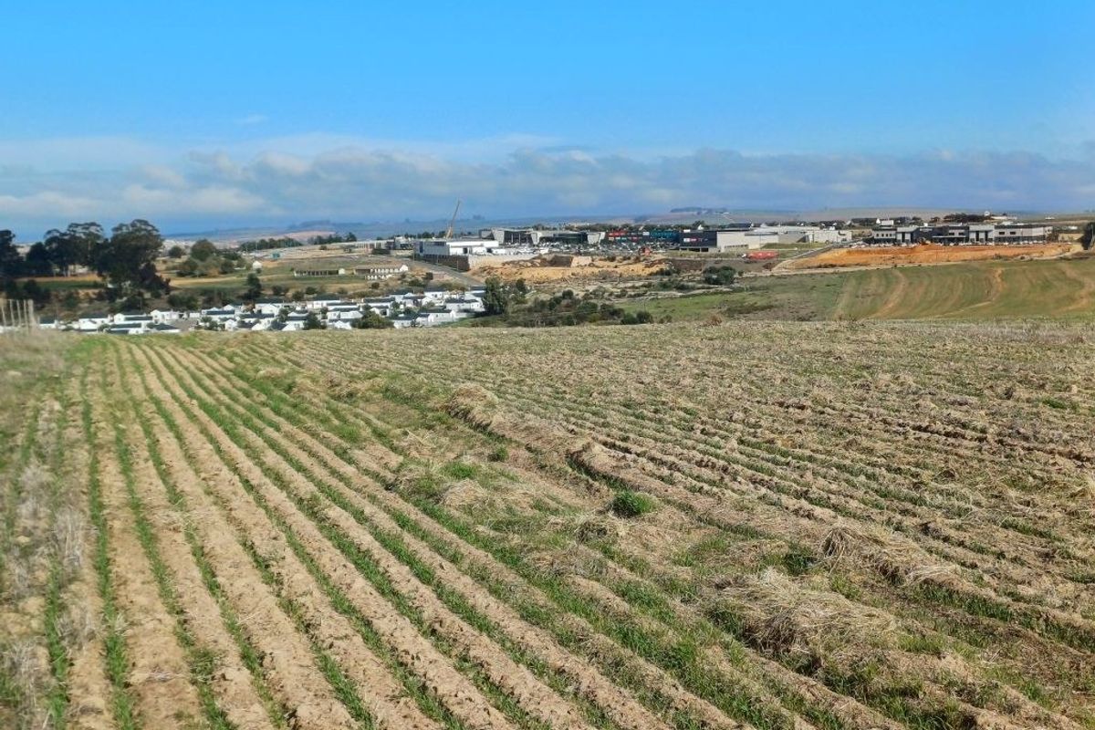 A wide-angle view of the surrounding landscape, featuring open fields in the foreground and a distant commercial development and residential area.