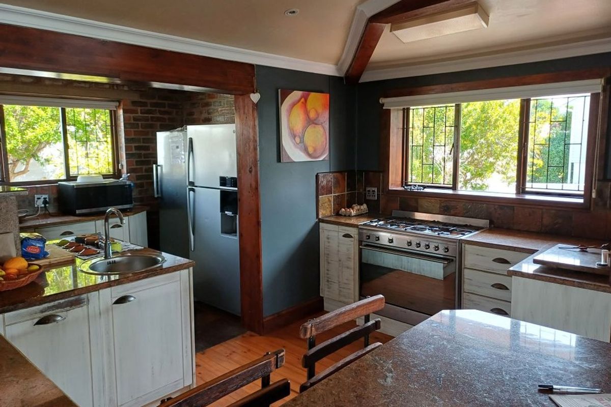 A rustic-style kitchen featuring granite countertops, exposed brick accents, timber ceiling beams, and a built-in gas stove with oven.