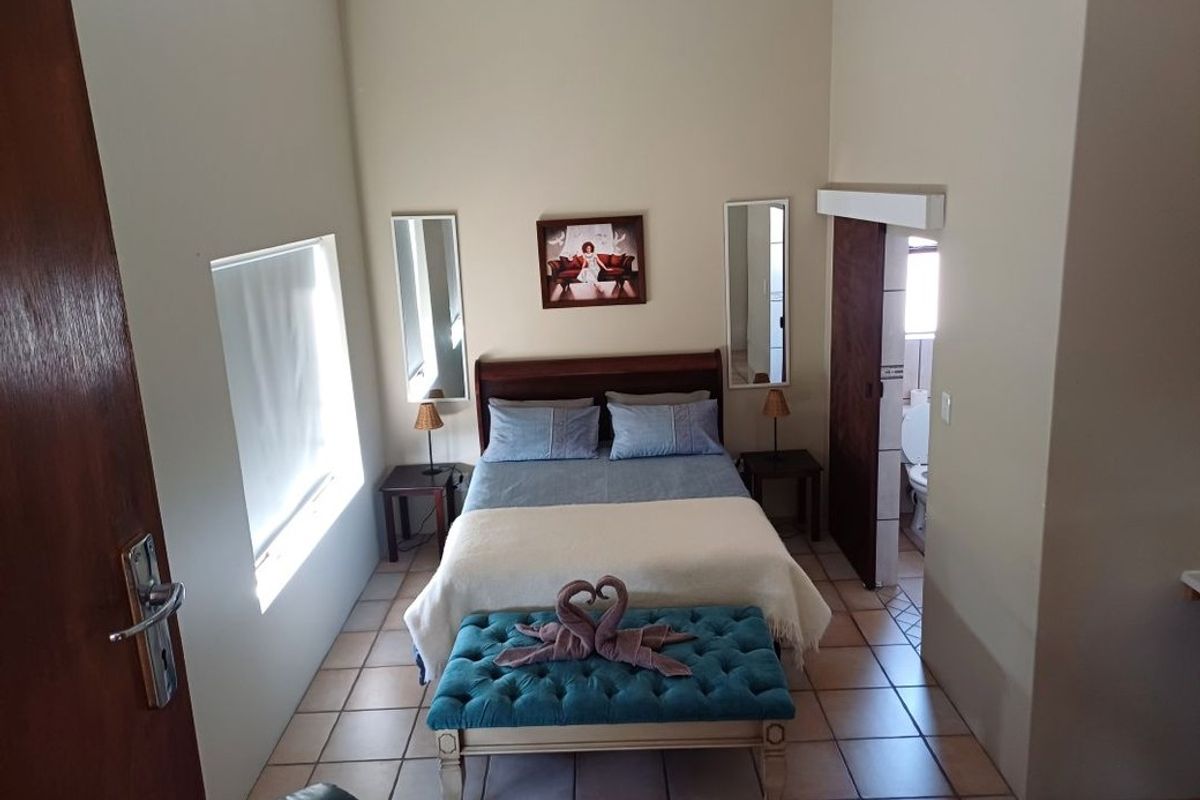 A bedroom featuring tiled flooring and direct access to an en-suite bathroom, providing a functional layout with neutral wall finishes.