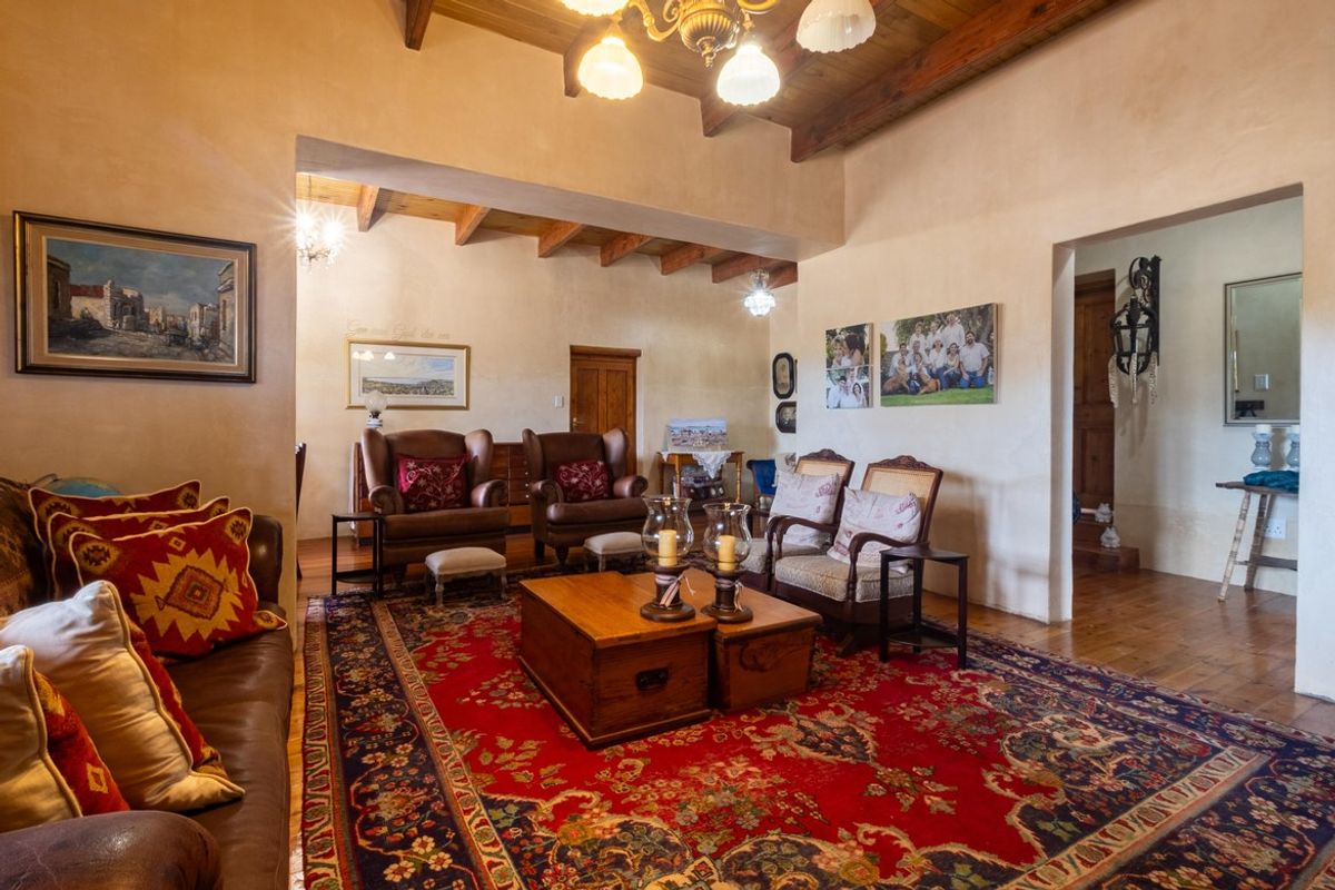 Spacious living room featuring exposed timber ceiling beams, warm wall finishes, and polished wooden flooring, creating a rustic and inviting atmosphere.