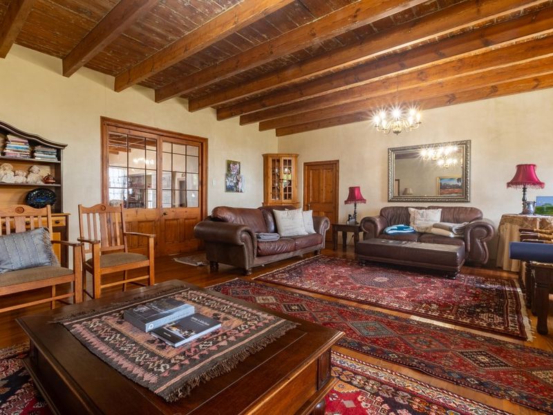 Spacious living room featuring exposed timber ceiling beams, polished hardwood flooring, and classic French doors leading to an adjacent room.