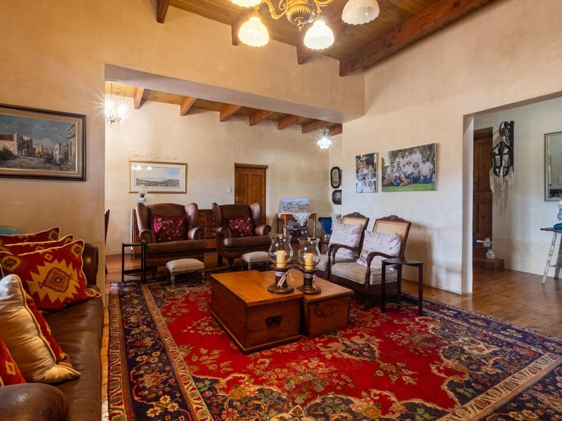 Spacious living room featuring exposed timber ceiling beams, warm wall finishes, and polished wooden flooring, creating a rustic and inviting atmosphere.