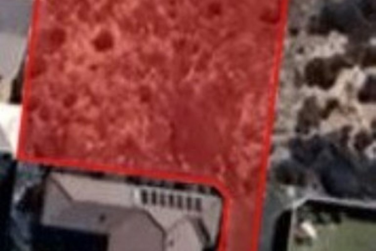 Aerial view of a vacant residential land parcel with property boundaries highlighted in red.