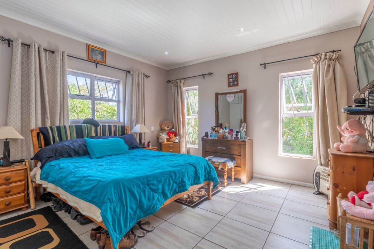 A spacious bedroom featuring tiled flooring, recessed ceiling lighting, and large windows that provide ample natural light.