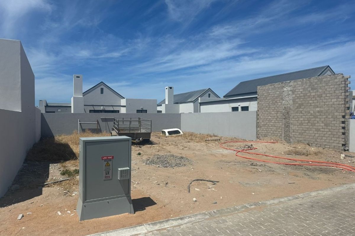An undeveloped rear yard area featuring boundary walls, an electrical utility box, and unfinished ground surfaces ready for landscaping.