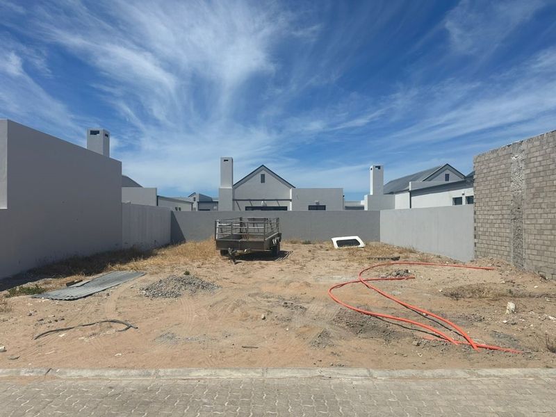 A vacant residential plot featuring boundary walls, ready for landscaping or development in a modern estate setting.