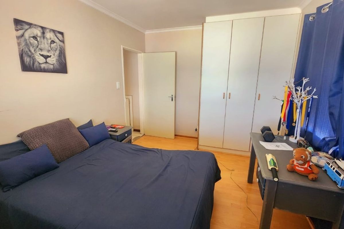 A functional bedroom featuring built-in wardrobes, laminate flooring, and neutral wall finishes, providing a comfortable and practical living space.